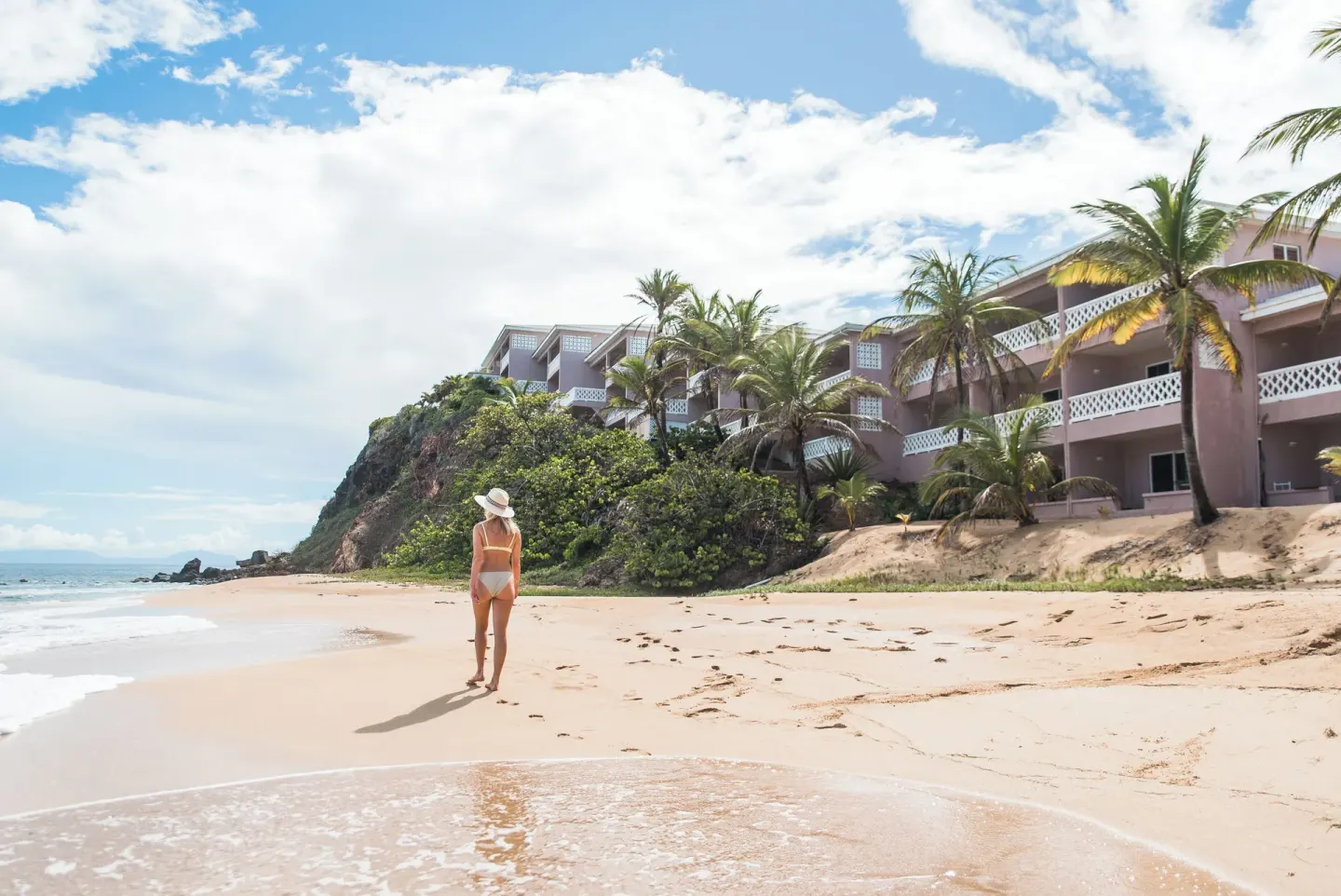 Beachfront guest buildings and palms above the sand at Curtain Bluff Resort.