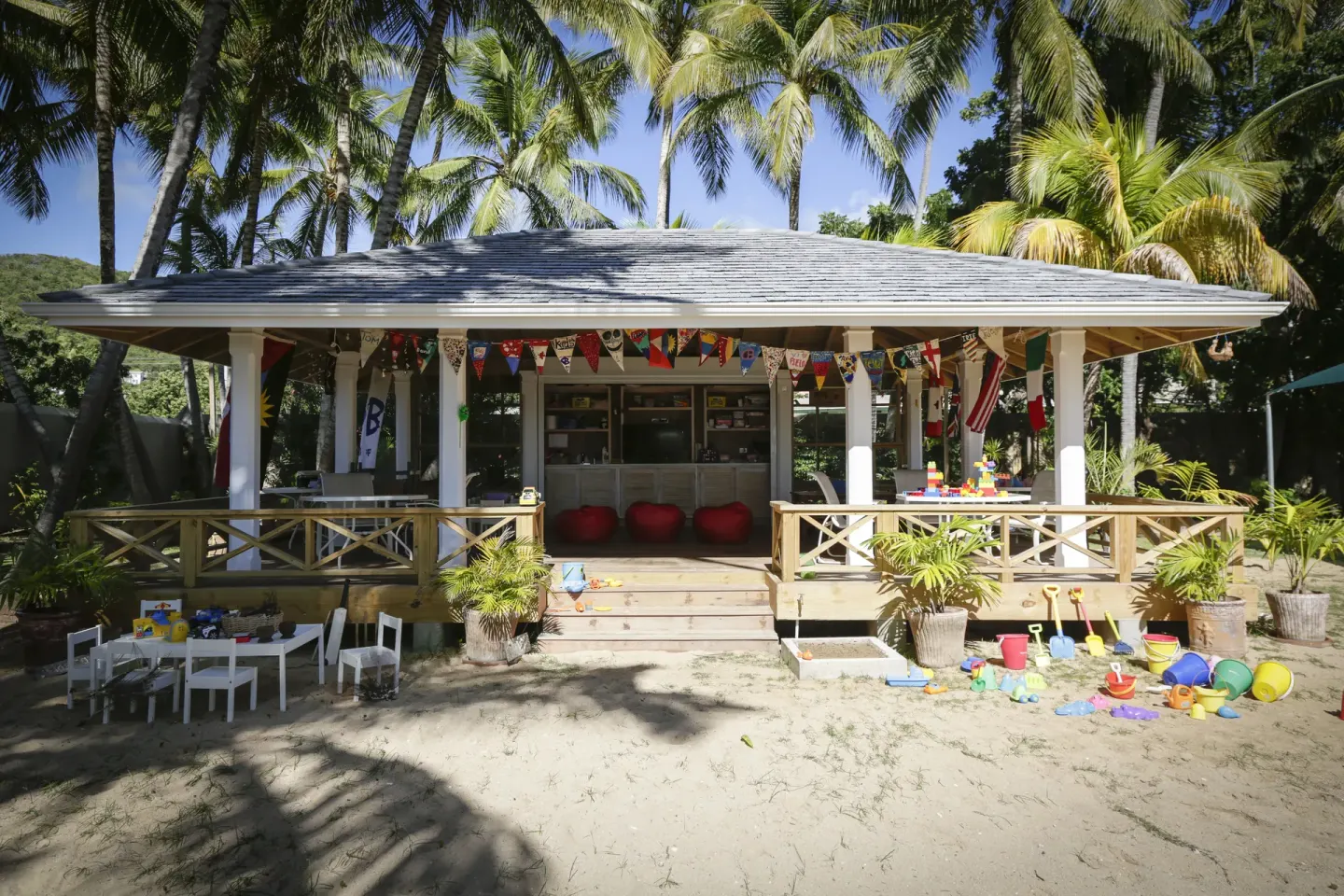 A children's club building with toys on the sand is shown at Curtain Bluff Resort.