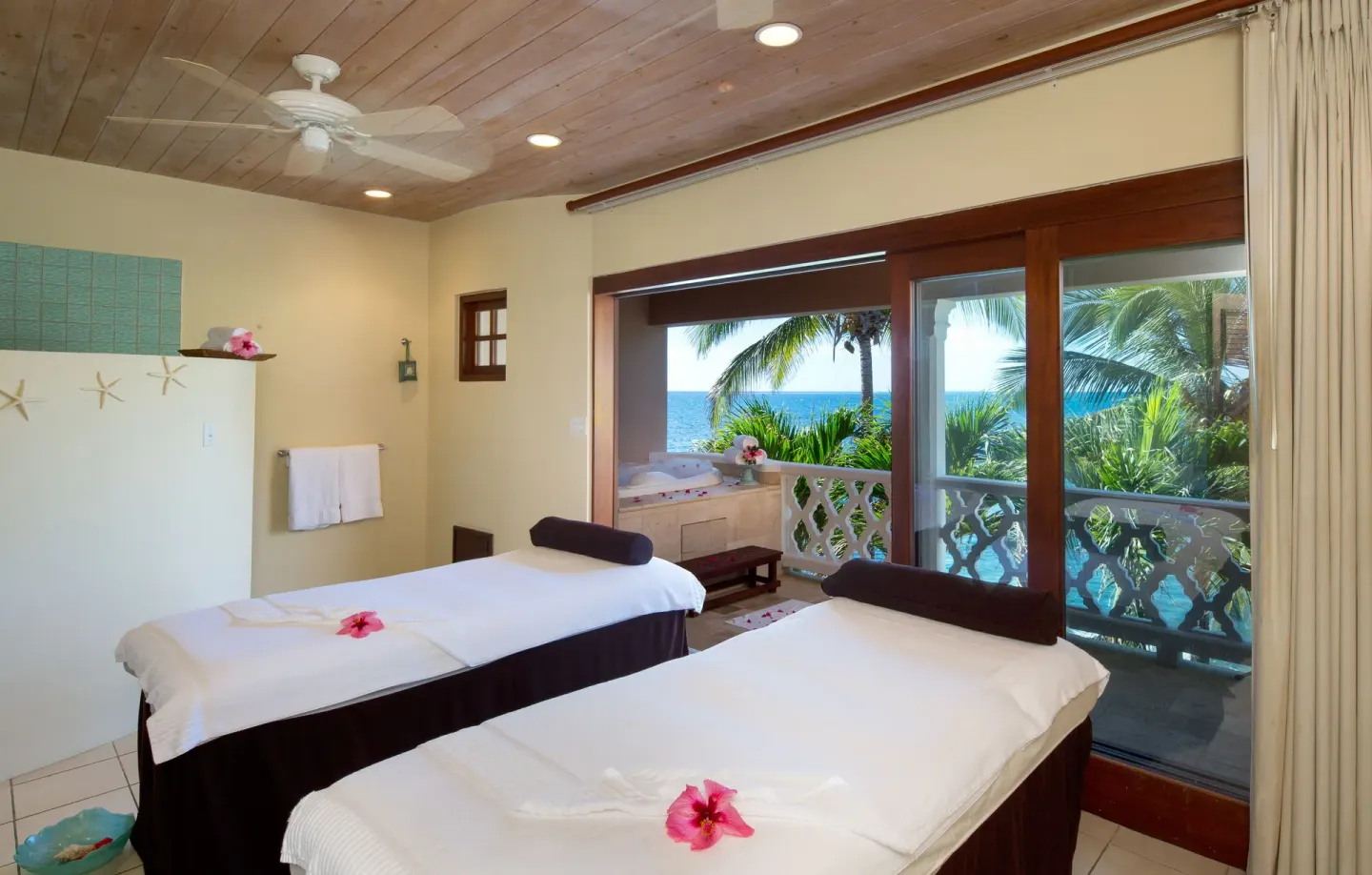 Two spa treatment tables overlook palms and the ocean at Curtain Bluff Resort.