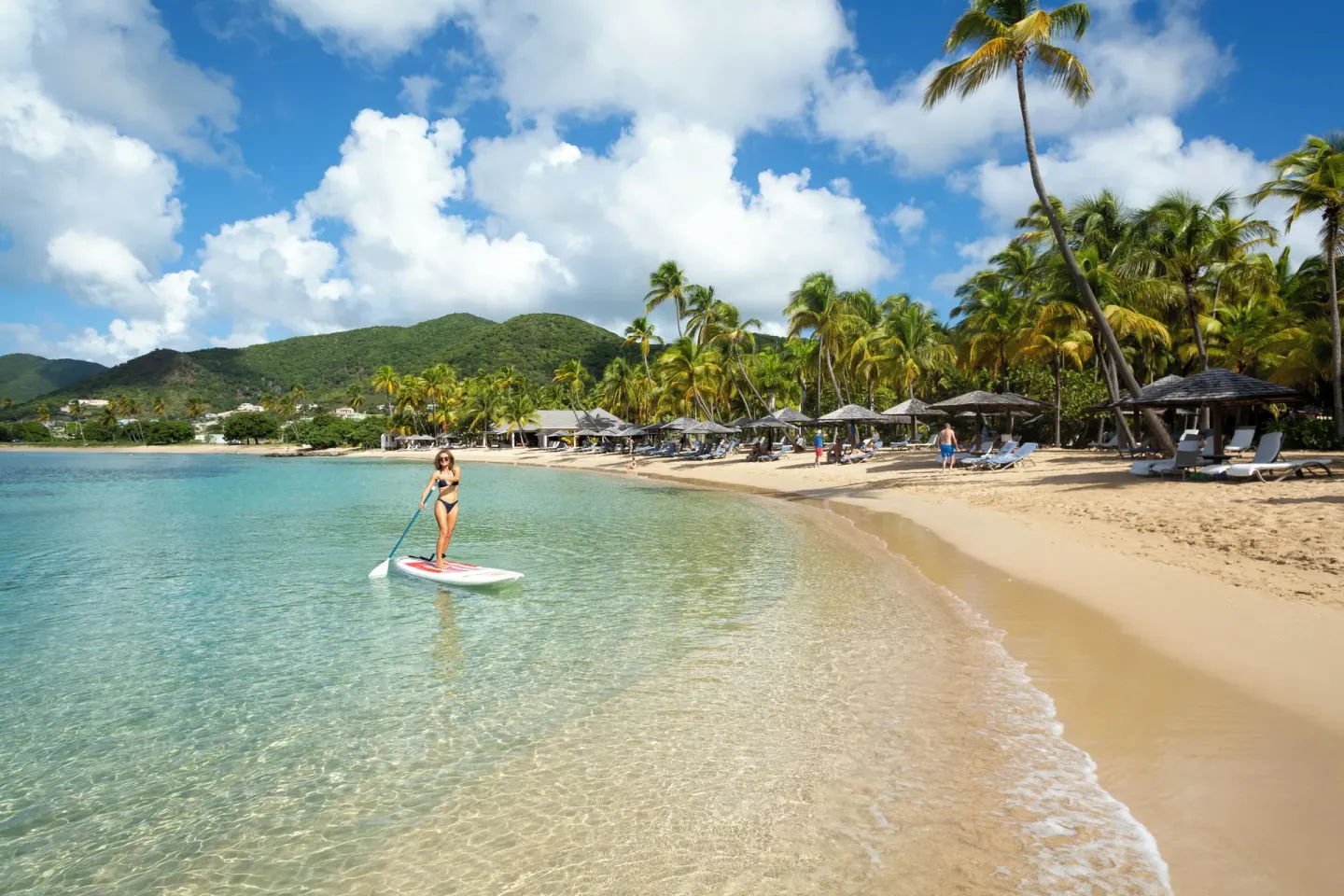 Paddleboarder in clear shallow water by the beach at Curtain Bluff Resort.