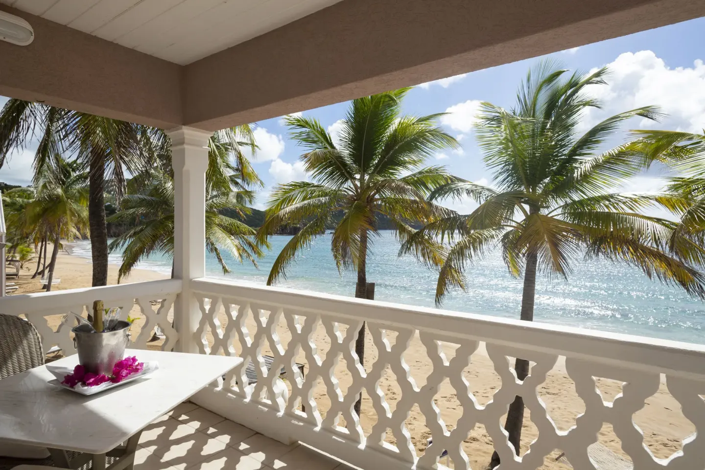 Shaded balcony with ocean view and palm trees at Curtain Bluff Resort.
