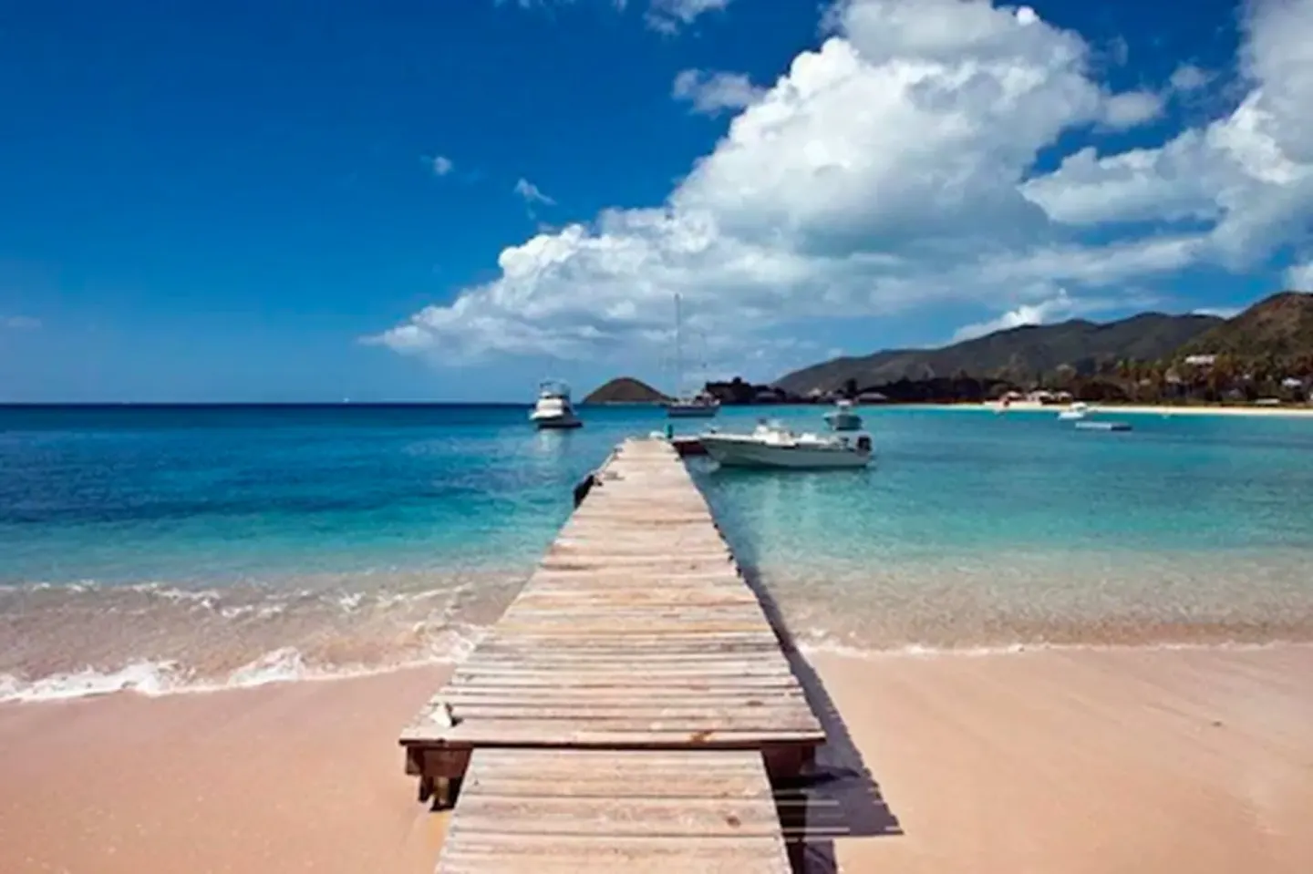 Wooden pier stretching into turquoise water at Curtain Bluff Resort.