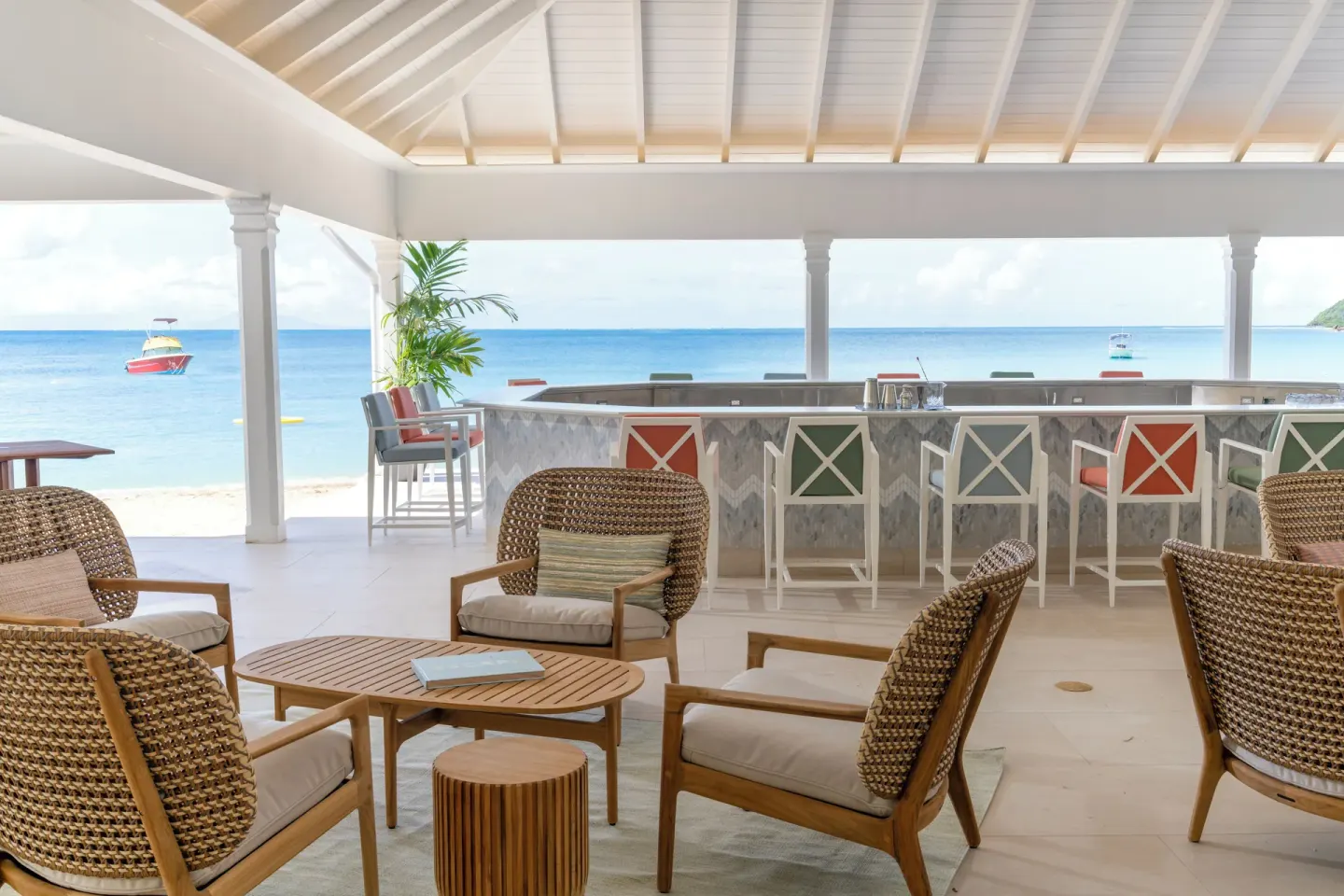 Beach bar seating with ocean view and colorful stools at Curtain Bluff Resort.