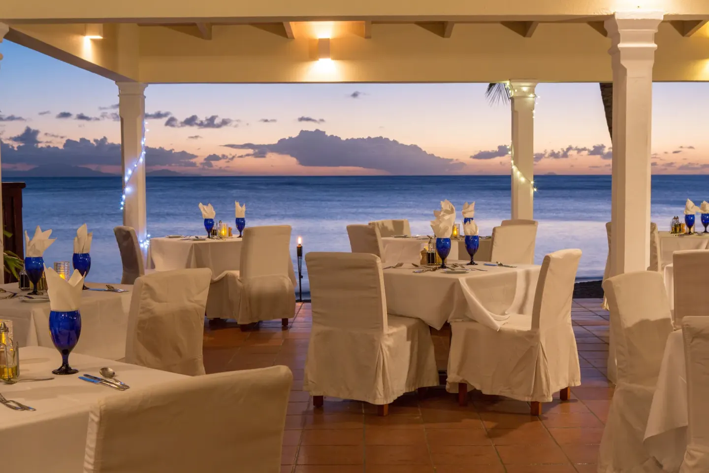 Oceanfront dining room set for sunset dinner at Curtain Bluff Resort.