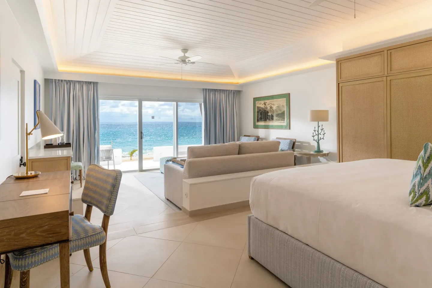 Junior Suite king bed, sitting area, and ocean-facing doors at Curtain Bluff Resort.
