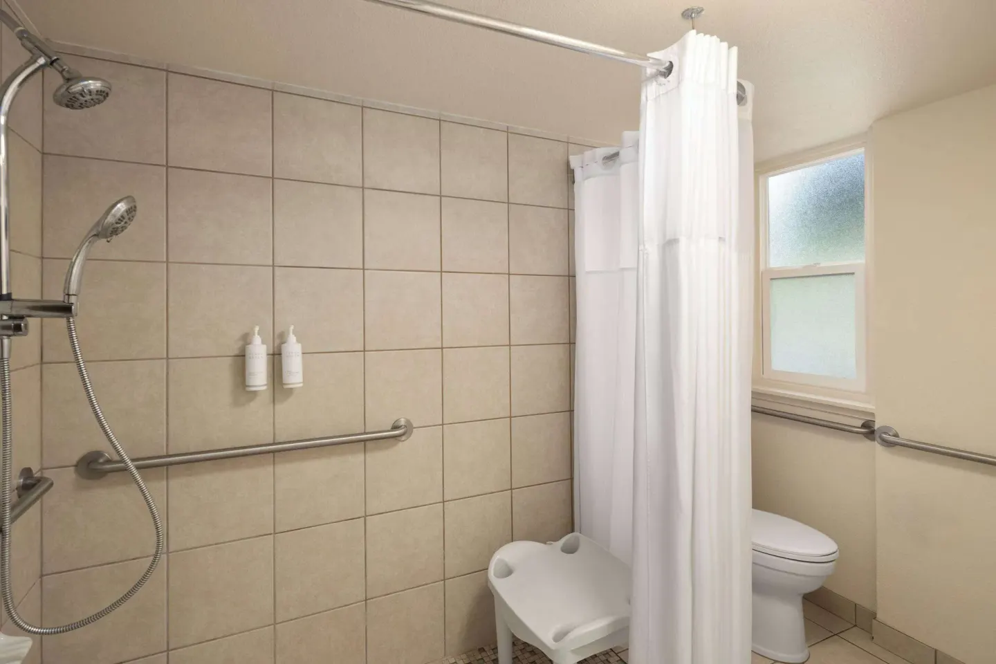Accessible bathroom shower with grab bars and shower chair at Days Inn Maui Oceanfront.