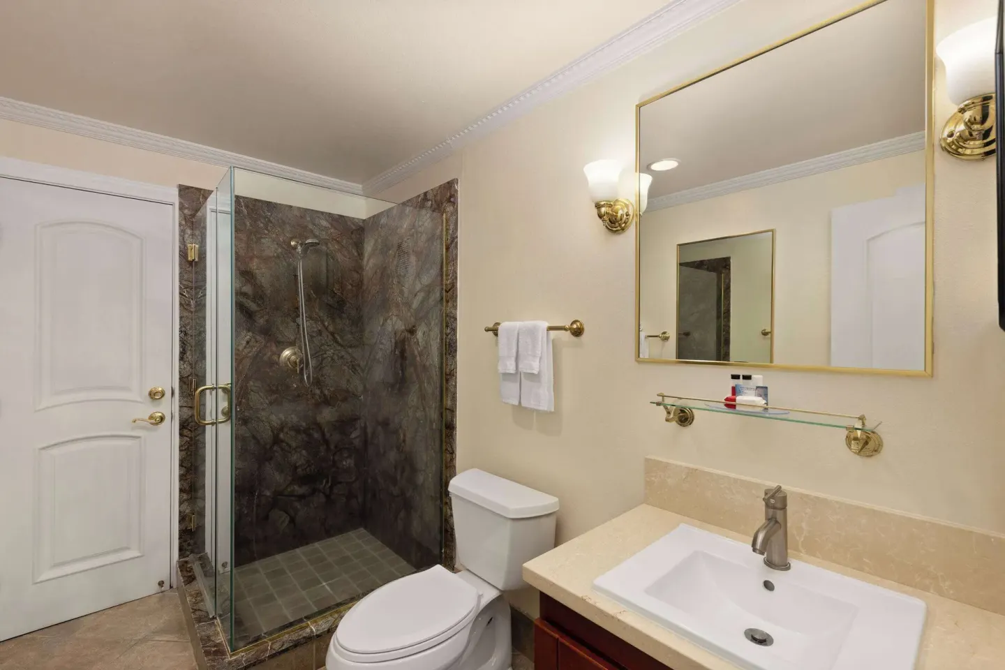 Bathroom with glass shower, toilet, and sink vanity at Days Inn Maui Oceanfront.