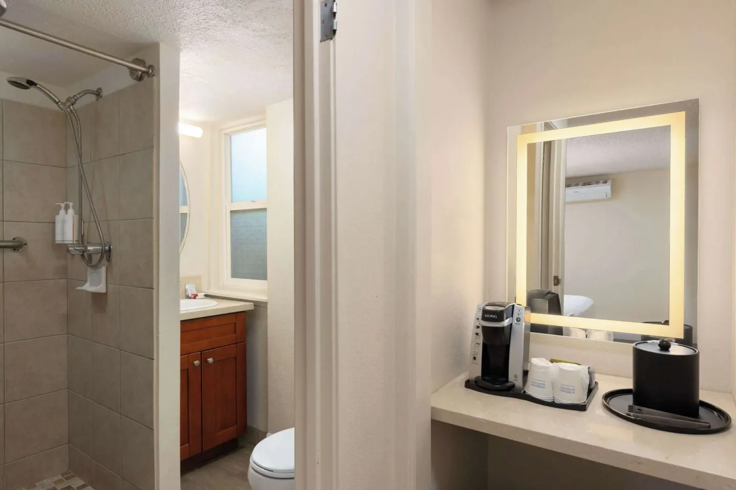 Bathroom with tiled shower and lit mirror counter at Days Inn Maui Oceanfront.