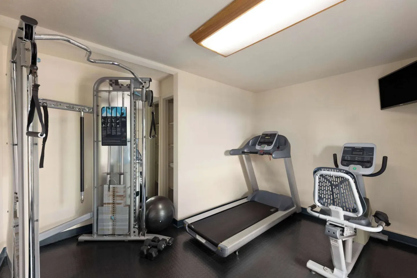 Fitness room with treadmill, exercise bike, and cable machine at Days Inn Maui Oceanfront.