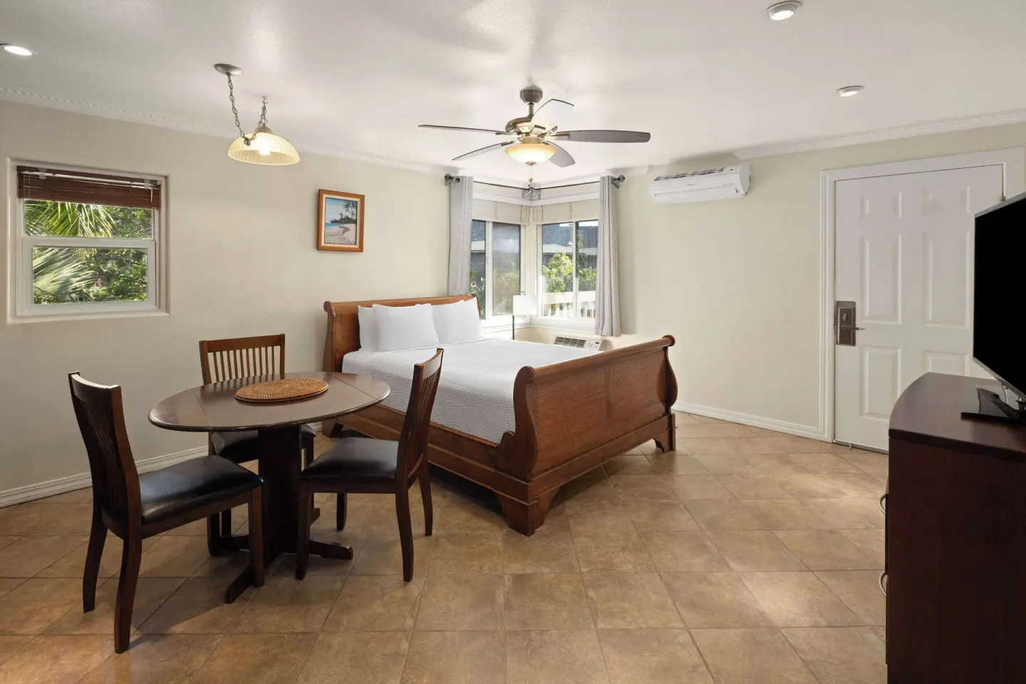 Guest room with king bed, dining table, ceiling fan, and TV at Days Inn Maui Oceanfront.