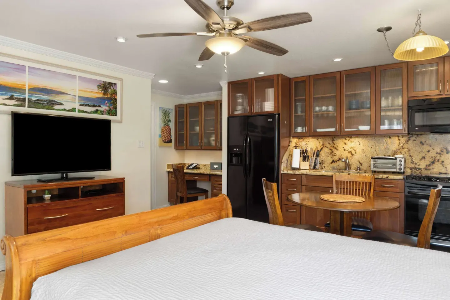 Guest room with king bed, kitchen, dining table, and TV at Days Inn Maui Oceanfront.