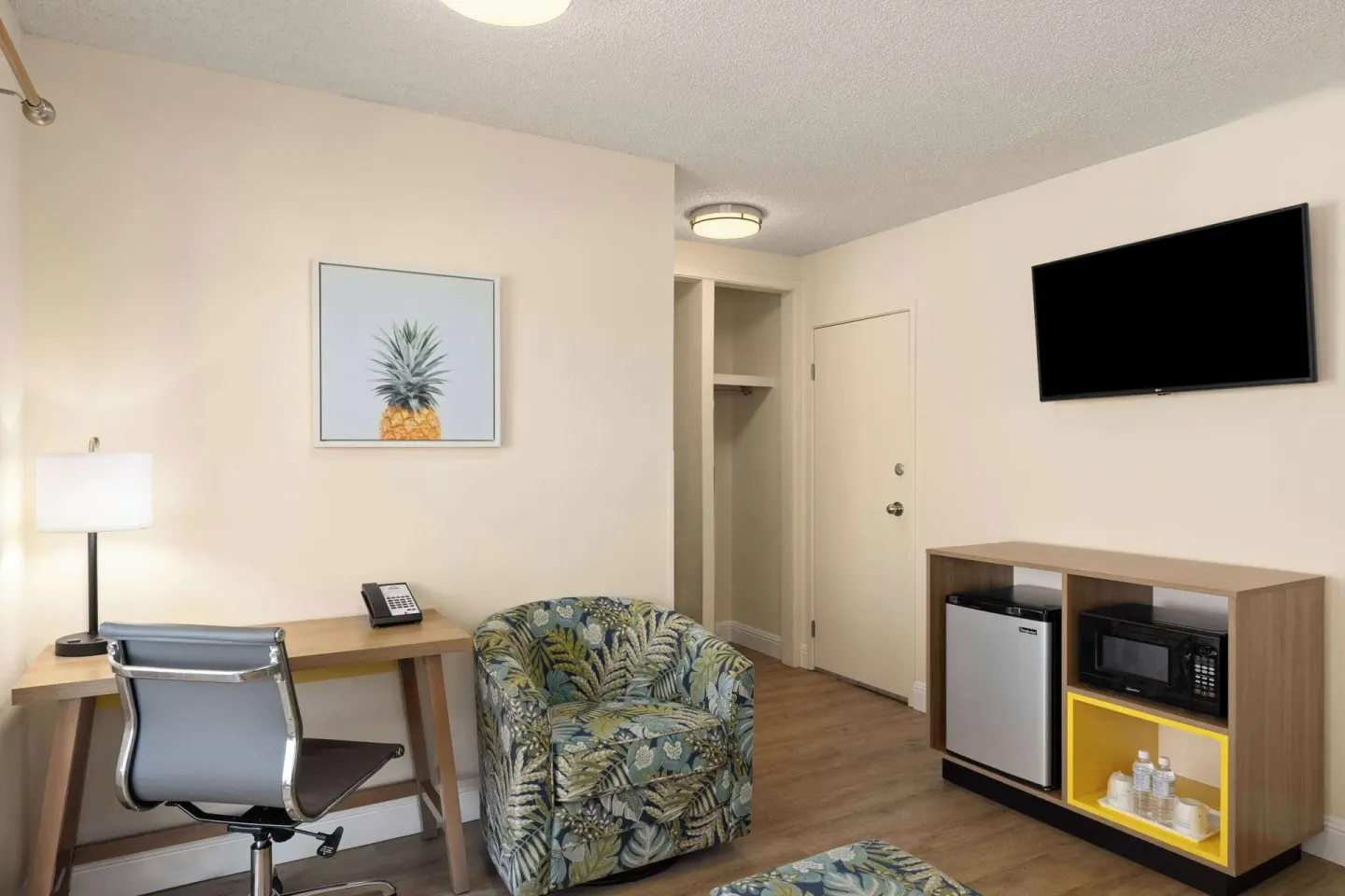 Guest room sitting area with desk, chair, TV, mini fridge, and microwave at Days Inn Maui Oceanfront.