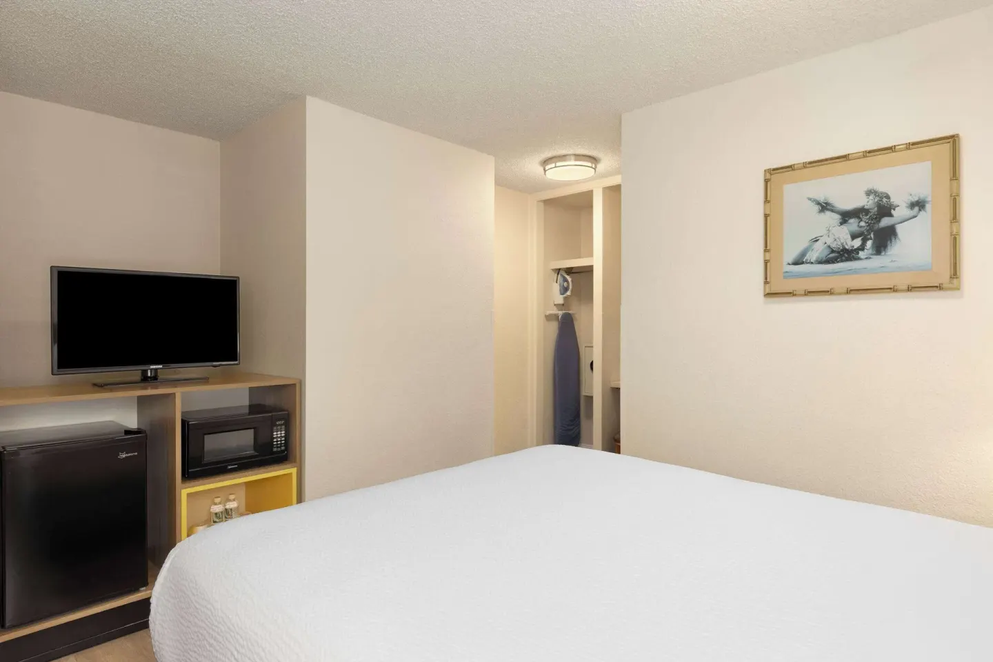 Guest room with bed, TV, mini fridge, microwave, and closet at Days Inn Maui Oceanfront.