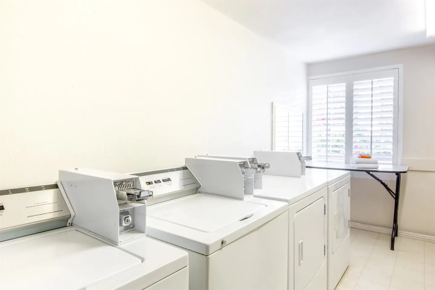 Laundry room with washers, dryers, and folding table at Days Inn Maui Oceanfront.