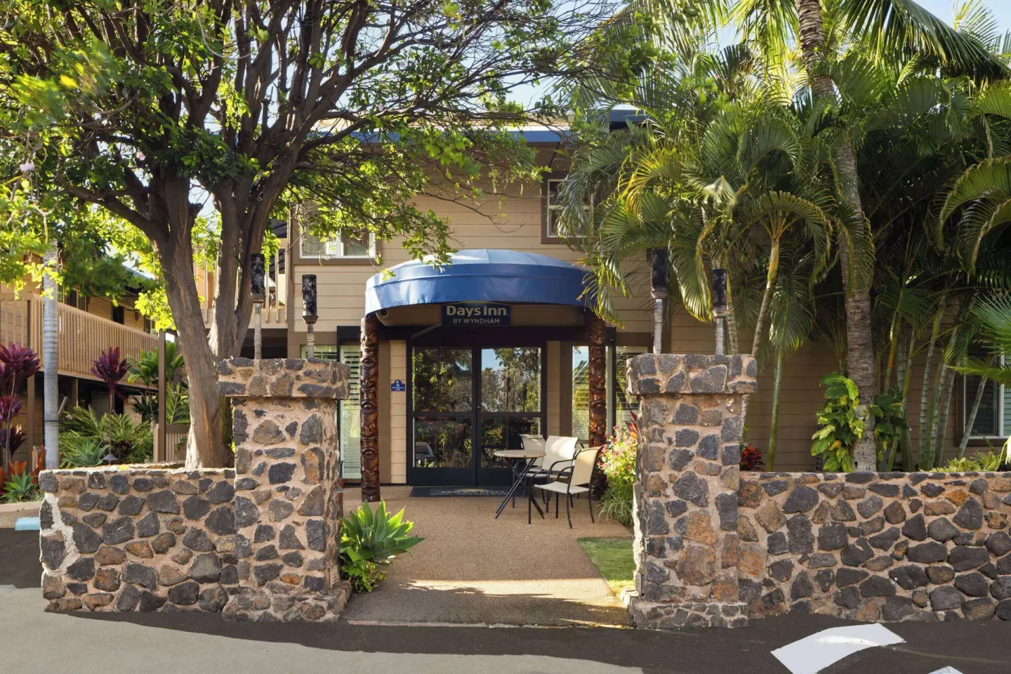 Stone entry walls and palms frame the entrance of Days Inn Maui Oceanfront.