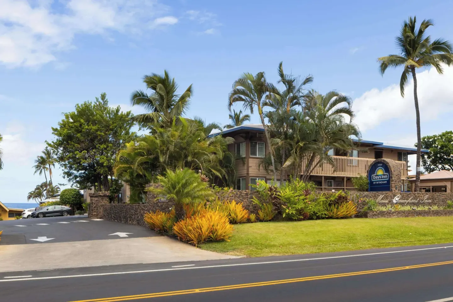 Street-front resort building with palms and landscaped lawn at Days Inn Maui Oceanfront.