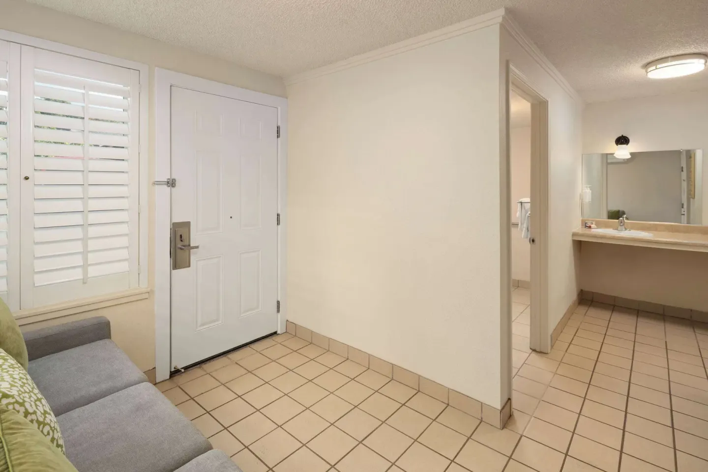 Suite entry area with sofa, tiled floor, door, and vanity at Days Inn Maui Oceanfront.