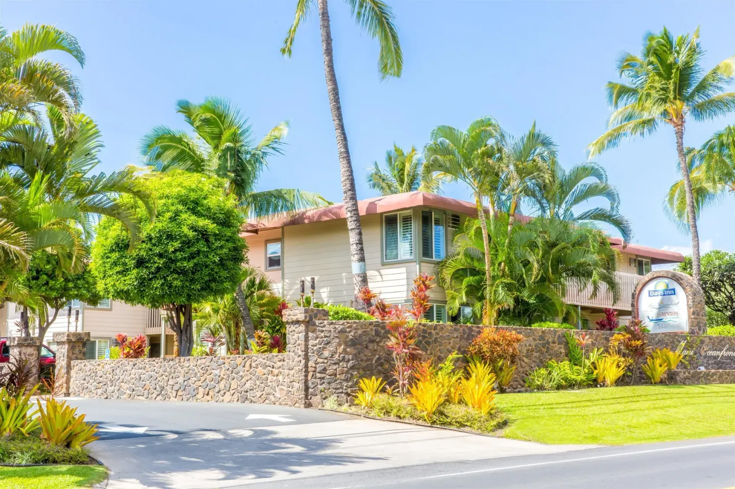 Tropical exterior with palm trees and entrance sign at Days Inn Maui Oceanfront.