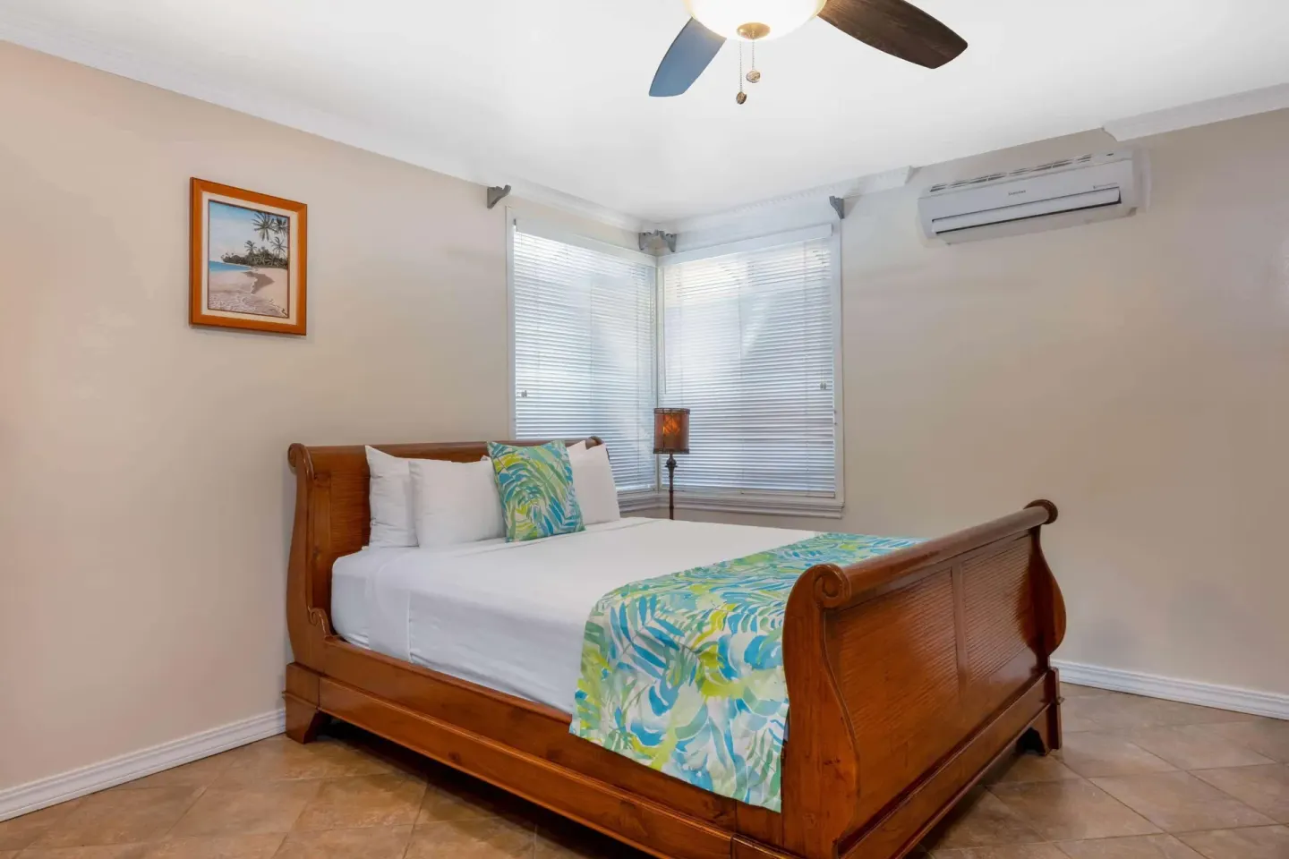 Kamehameha Studio Suite bed with windows and ceiling fan at Days Inn Maui Oceanfront.