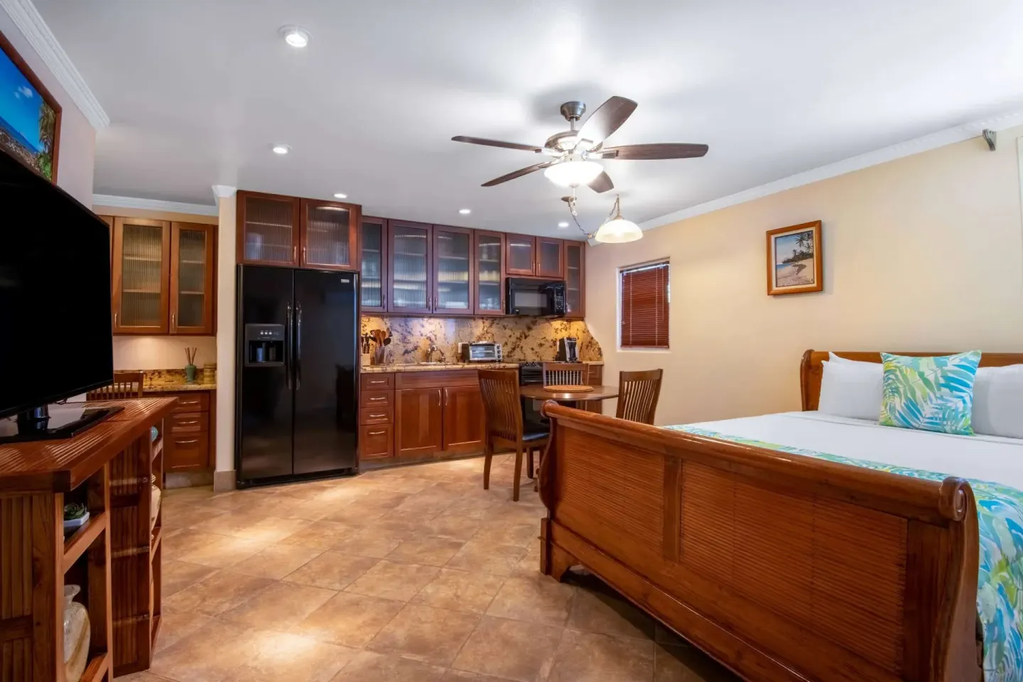 Kamehameha Studio Suite with kitchen cabinets, bed, and TV at Days Inn Maui Oceanfront.