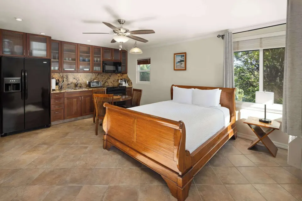 Kamehameha Studio Suite with bed, kitchen, and large window at Days Inn Maui Oceanfront.