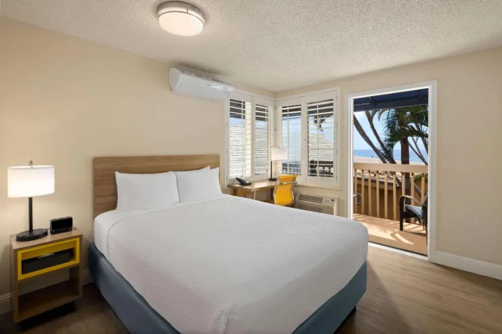 Partial ocean view guest room with king bed and balcony at Days Inn Maui Oceanfront.