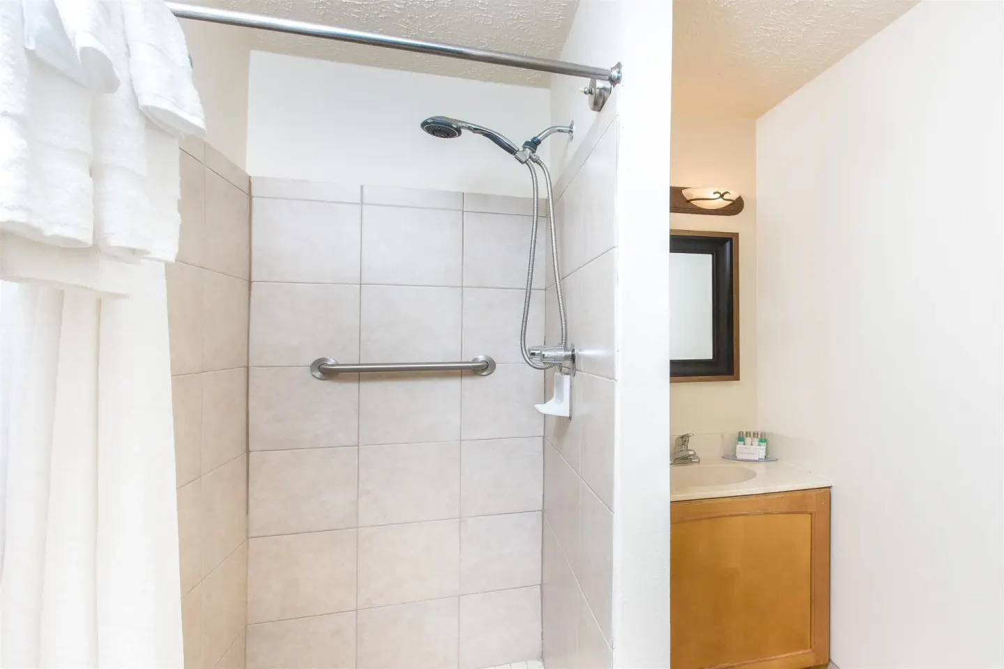 Standard Room bathroom with tiled shower and vanity at Days Inn Maui Oceanfront.
