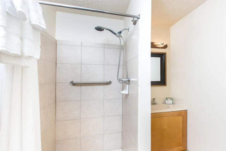 Standard Room bathroom with tiled shower and vanity at Days Inn Maui Oceanfront.