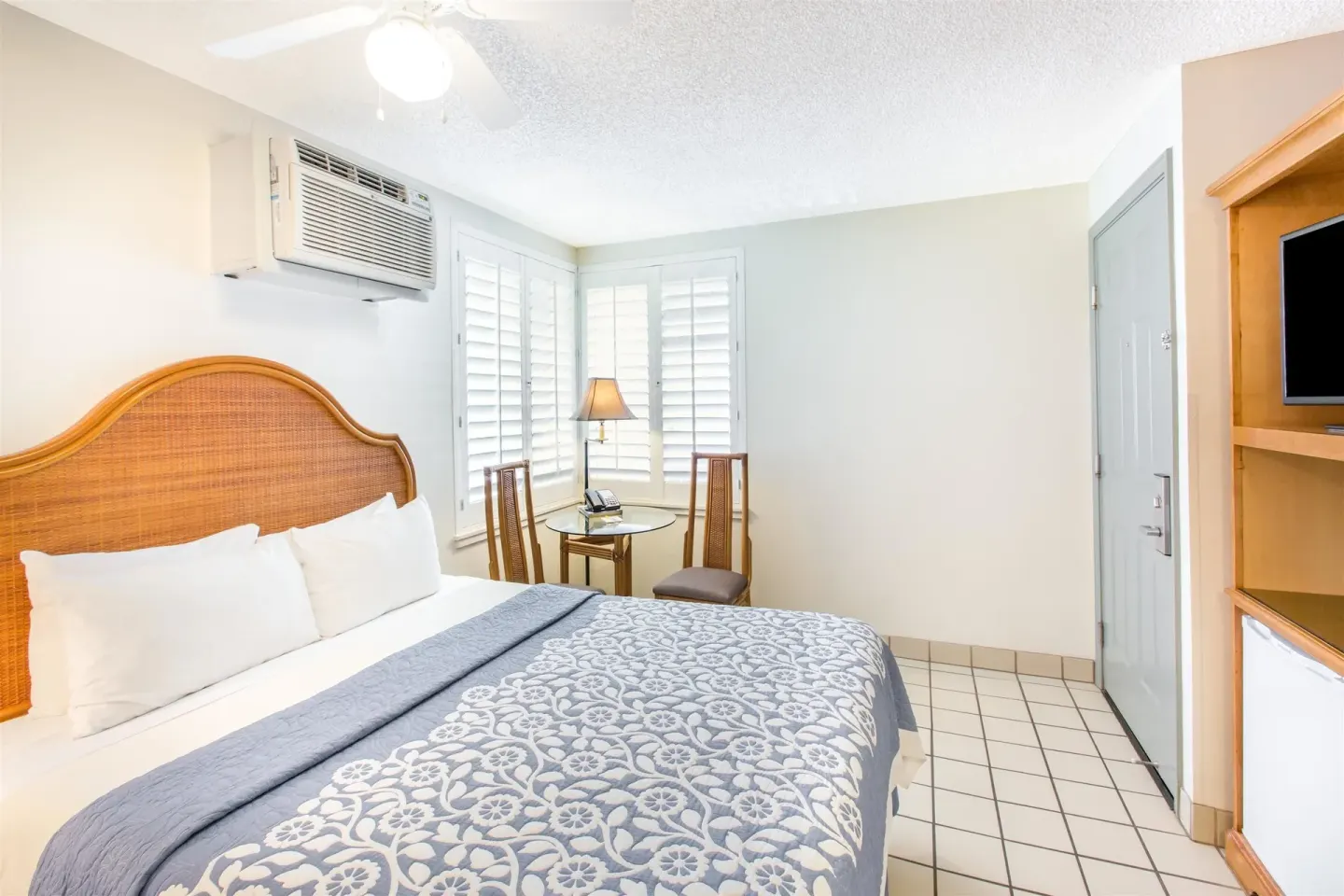 Standard Room with one bed, corner table, and entry door at Days Inn Maui Oceanfront.
