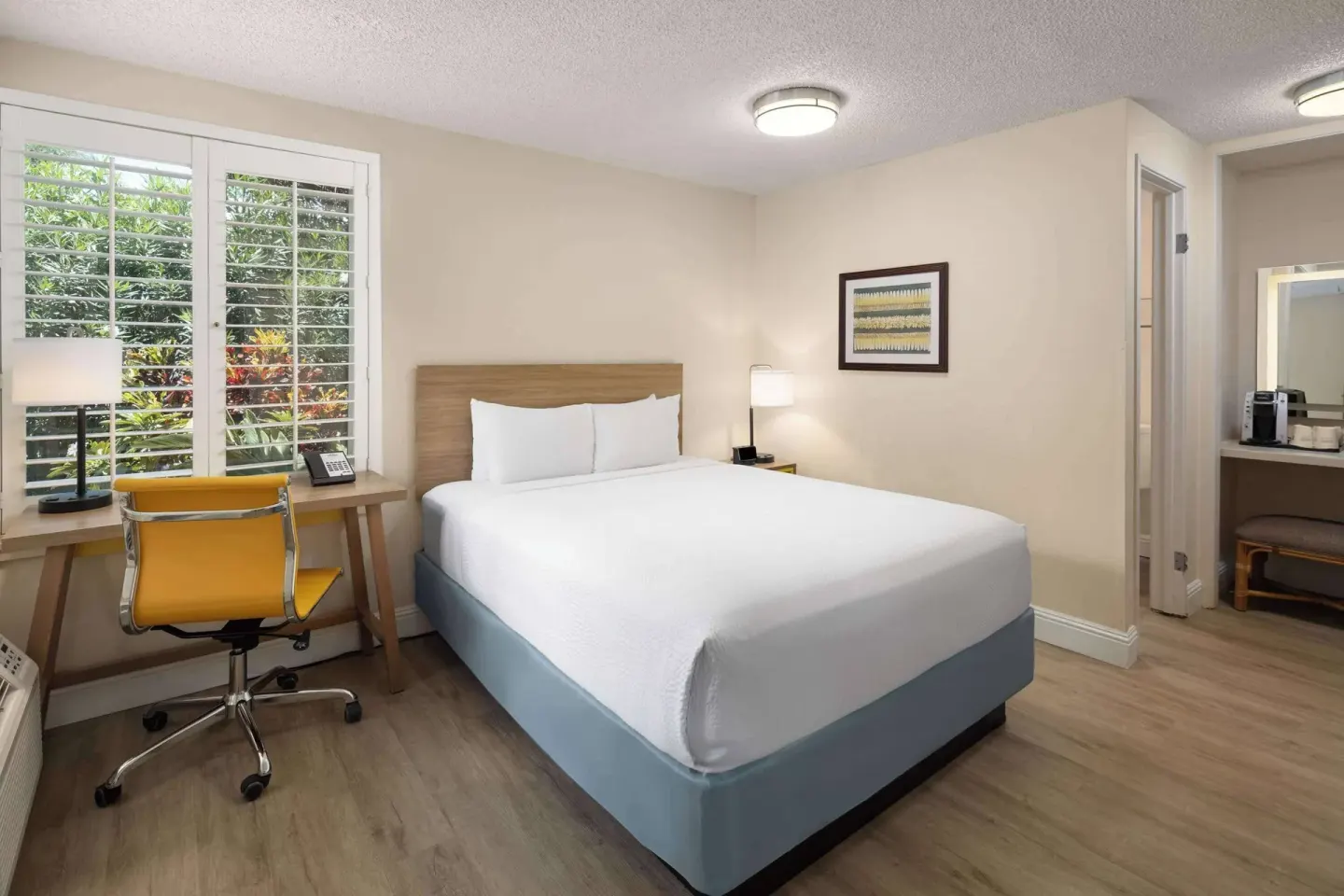 Standard Room with one bed, desk, and shuttered window at Days Inn Maui Oceanfront.