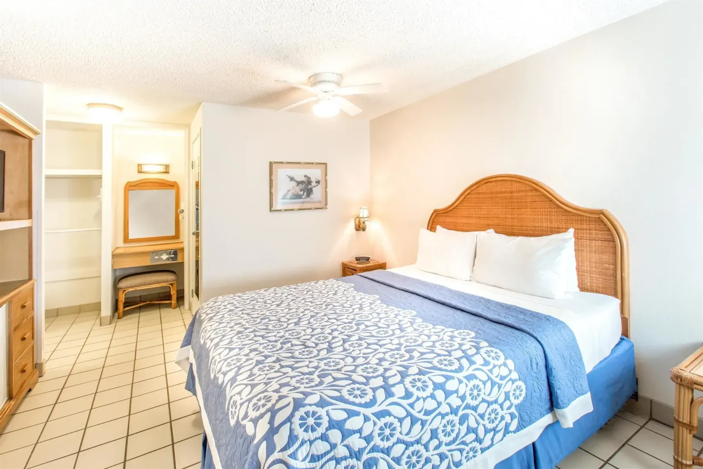 Standard Room with one bed, vanity area, and tile floor at Days Inn Maui Oceanfront.