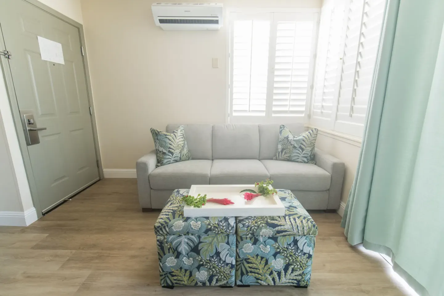 Sofa, shutters, and floral ottoman in a suite living area at Days Inn Maui Oceanfront.