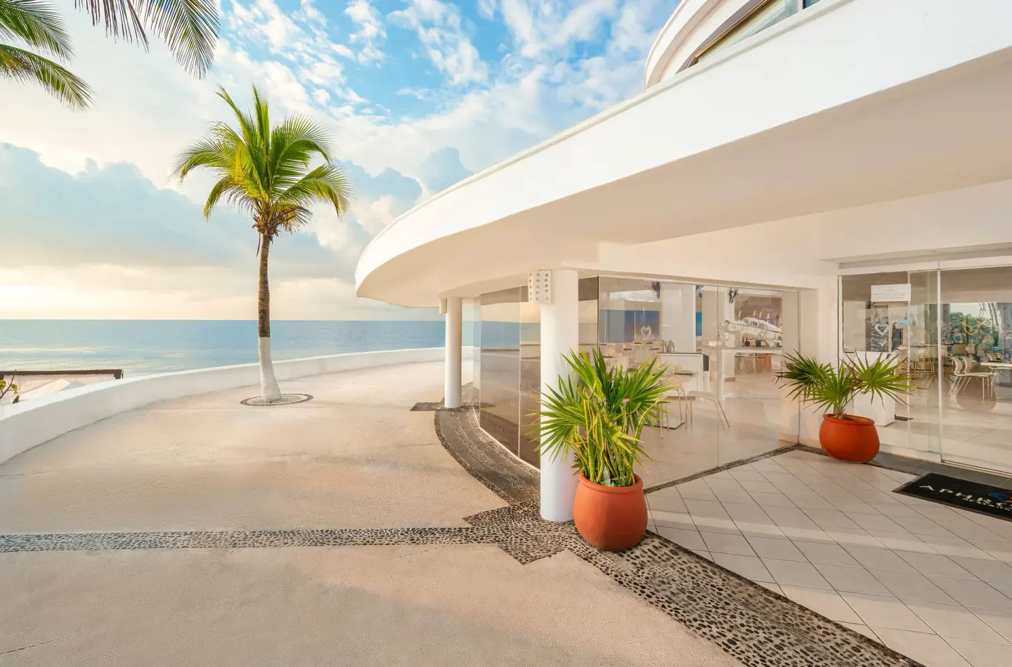 Curved beachfront building and palm-lined terrace at Desire Pearl Riviera Maya Resort.