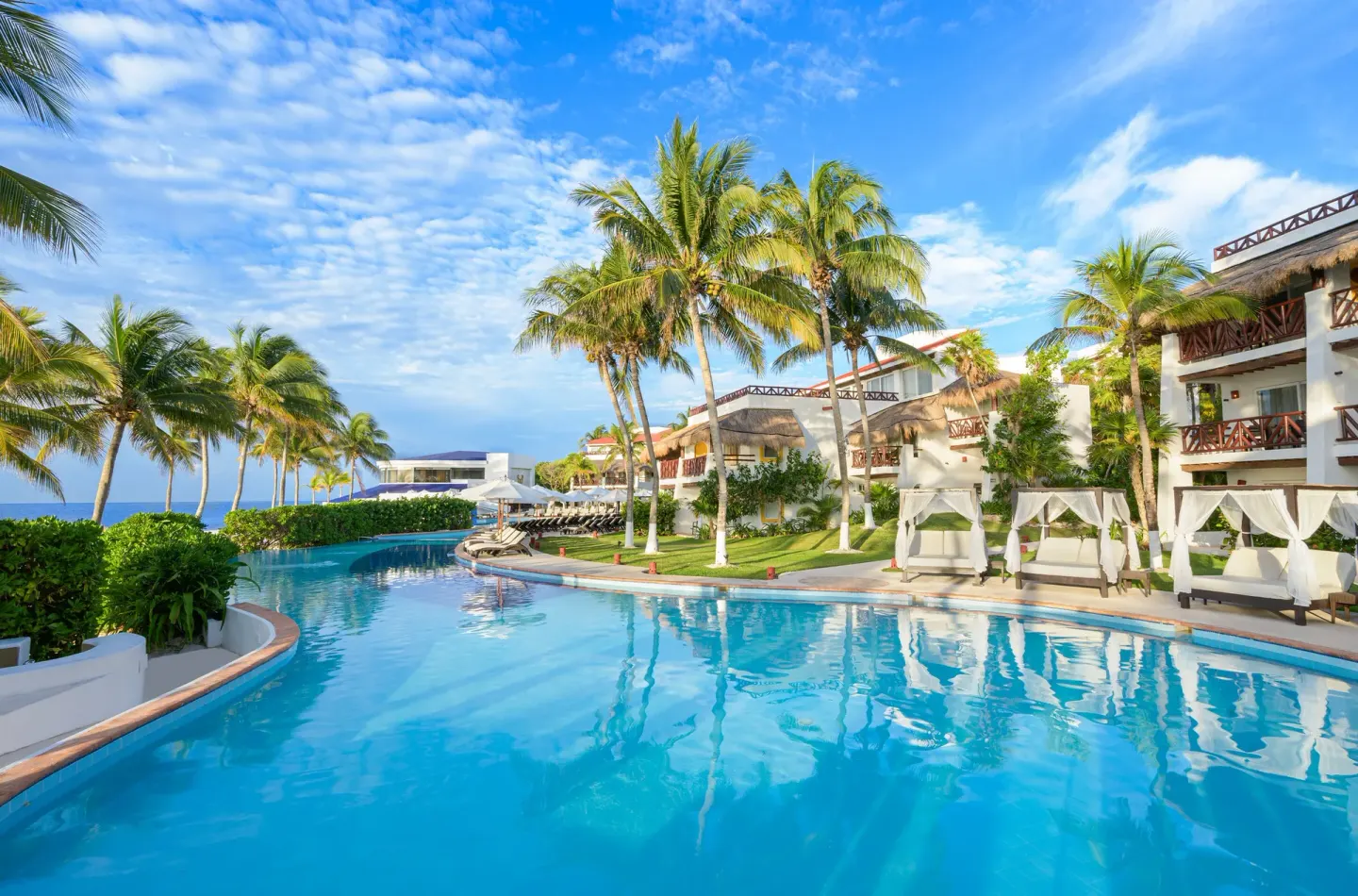 Lagoon-style pool with palm reflections at Desire Pearl Riviera Maya Resort.