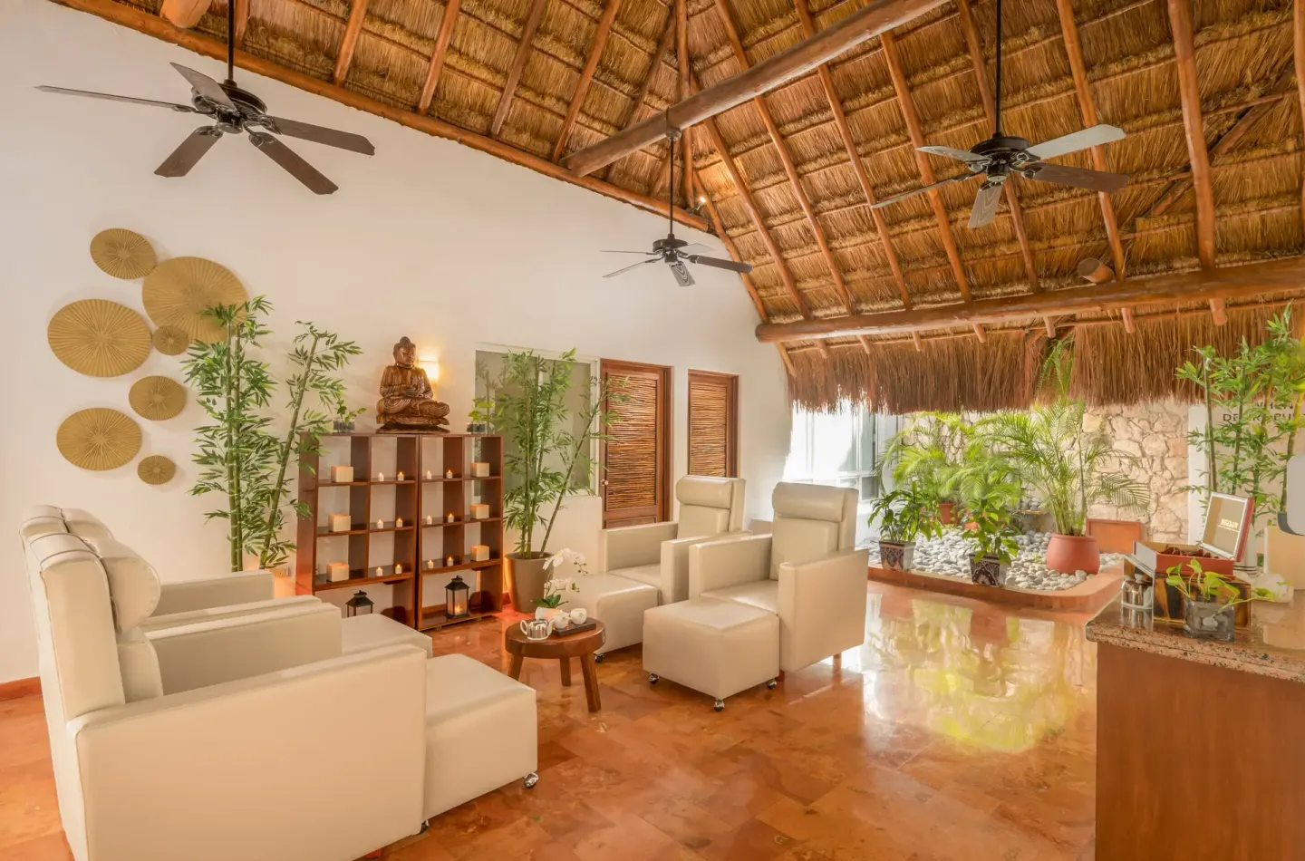 Spa relaxation lounge with white chairs and thatched ceiling at Desire Pearl Riviera Maya Resort.