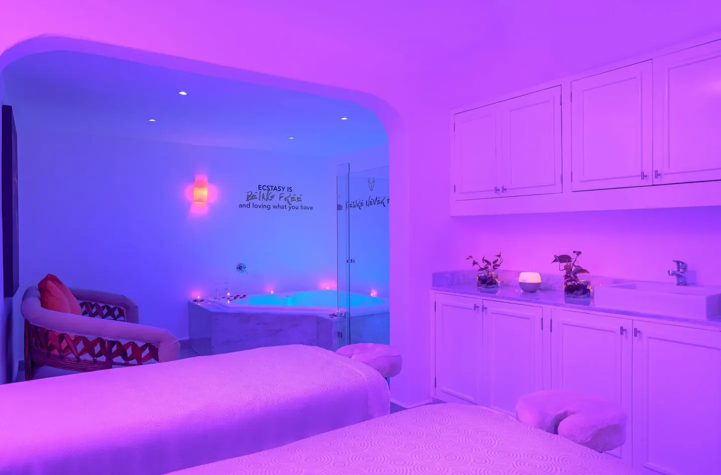 Spa treatment room with massage beds and glowing tub at Desire Pearl Riviera Maya Resort.