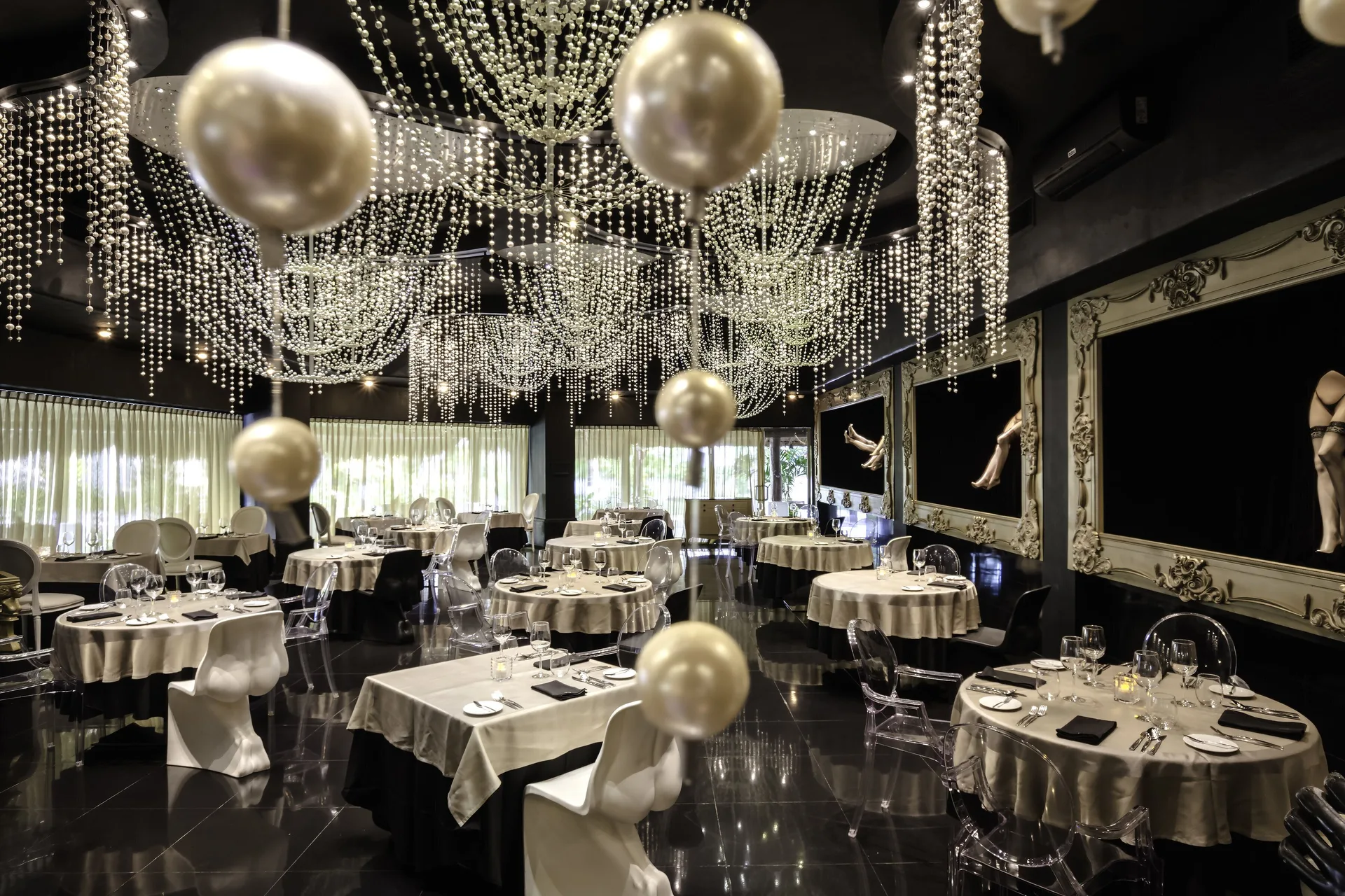 Elegant black dining room with crystal chandeliers at Desire Pearl Riviera Maya Resort.