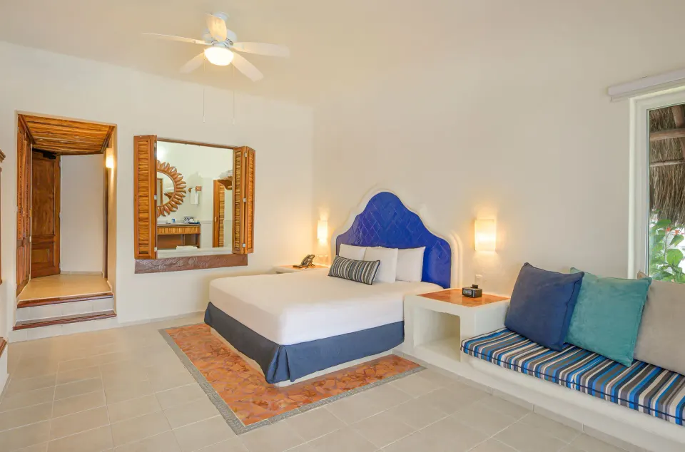 Junior Suite with king bed and cushioned seating at Desire Pearl Riviera Maya Resort.
