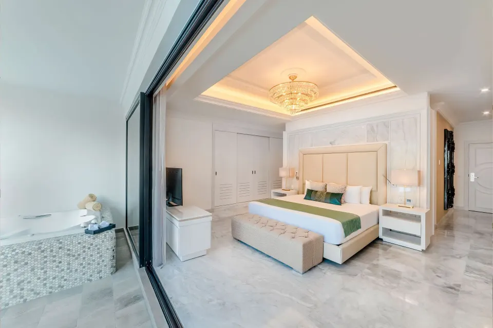 Mansion Jacuzzi Suite king bed beside a private jacuzzi at Desire Pearl Riviera Maya Resort.
