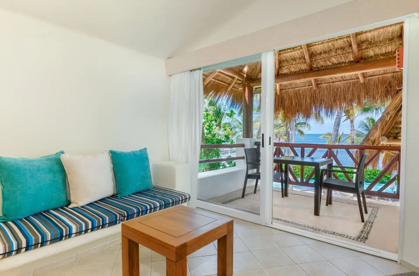 Ocean View room lounge with striped bench and ocean-facing balcony at Desire Pearl Riviera Maya Resort.