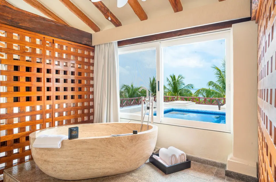 Penthouse Passion Suite bathtub by terrace window at Desire Pearl Riviera Maya Resort.