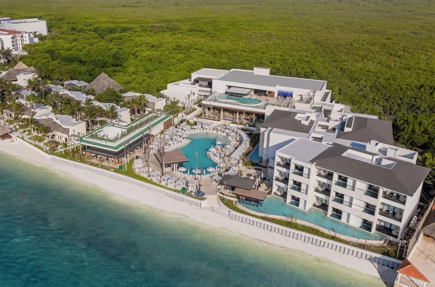 Aerial view of pools, beachfront buildings, and coastline at Desire Riviera Maya Resort.