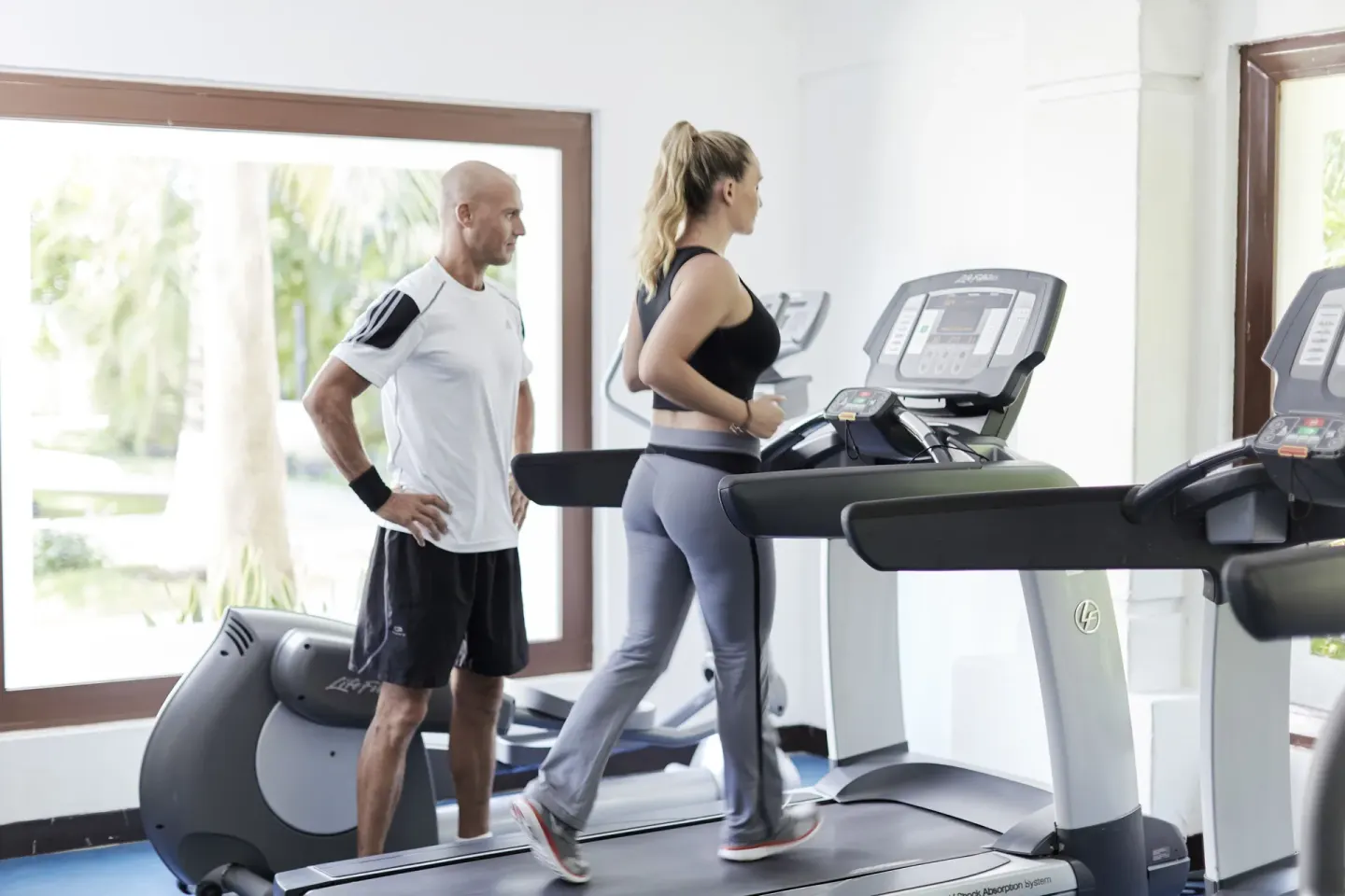 Fitness room with treadmills and guests exercising at Desire Riviera Maya Resort.