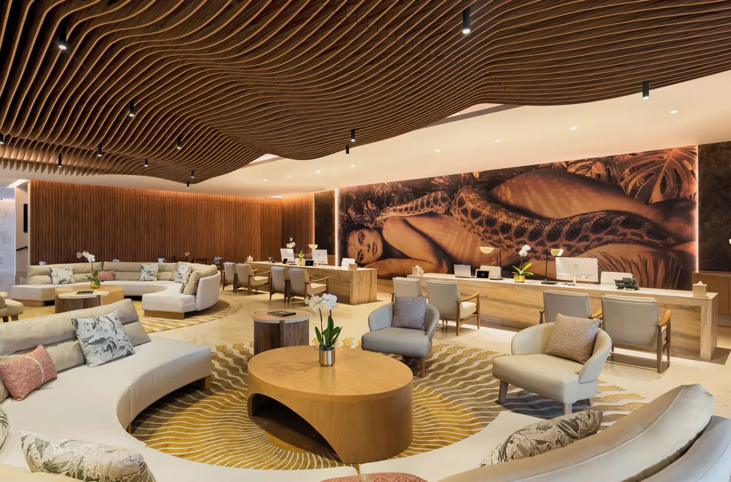 Lobby lounge with curved sofas, reception desks and a wood-slat ceiling at Desire Riviera Maya Resort.