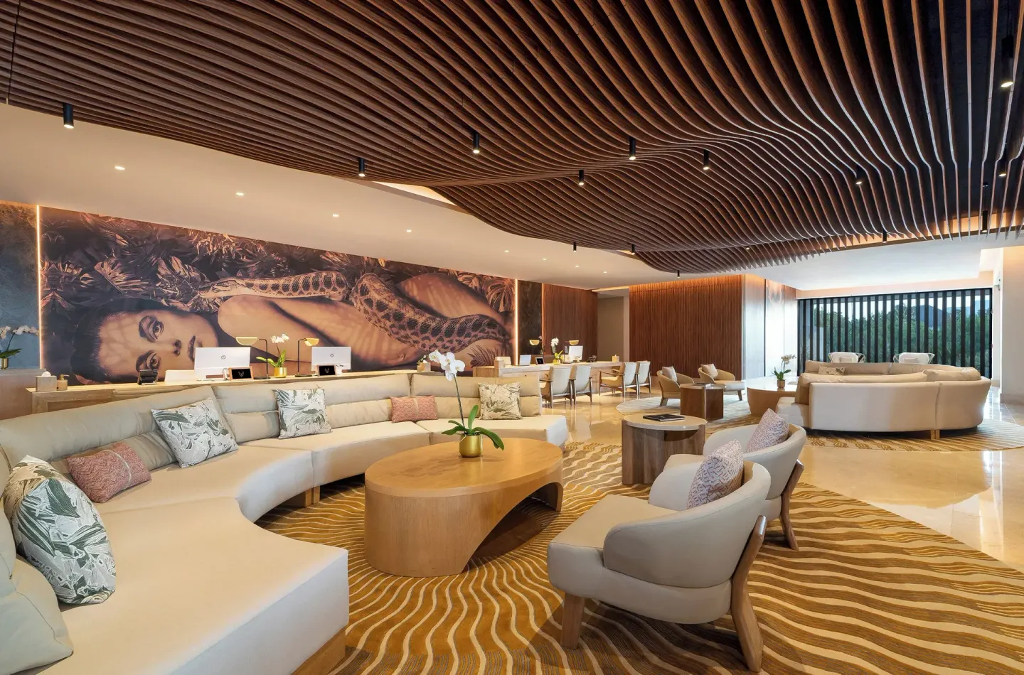 Spacious lobby with lounge seating, reception desks and a rippled wood ceiling at Desire Riviera Maya Resort.
