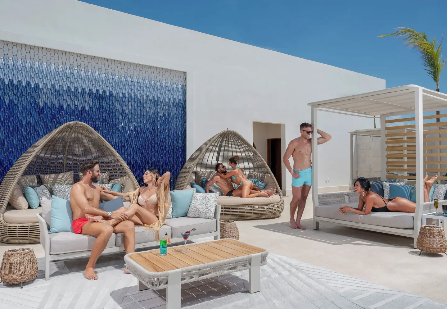 Rooftop-style lounge with daybeds, egg chairs, and guests at Desire Riviera Maya Resort.