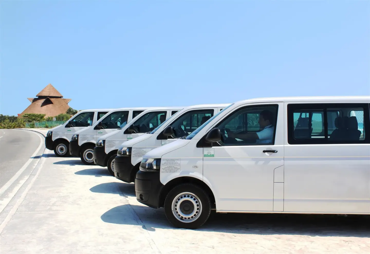 White passenger vans lined up on a resort driveway at Desire Riviera Maya Resort.