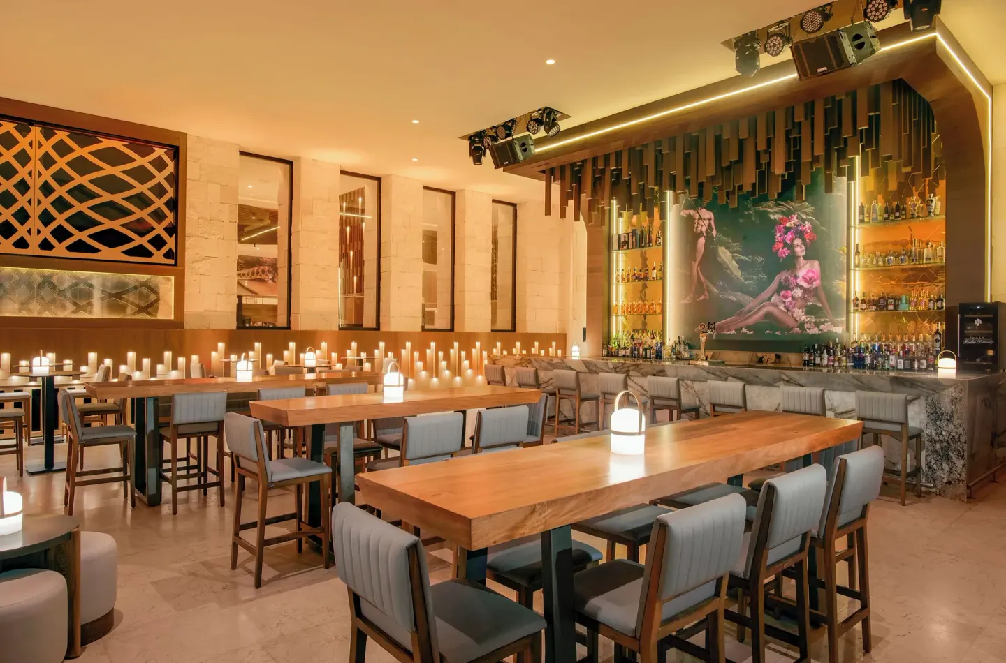 Candlelit lobby bar with high tables and backlit shelves at Desire Riviera Maya Resort.