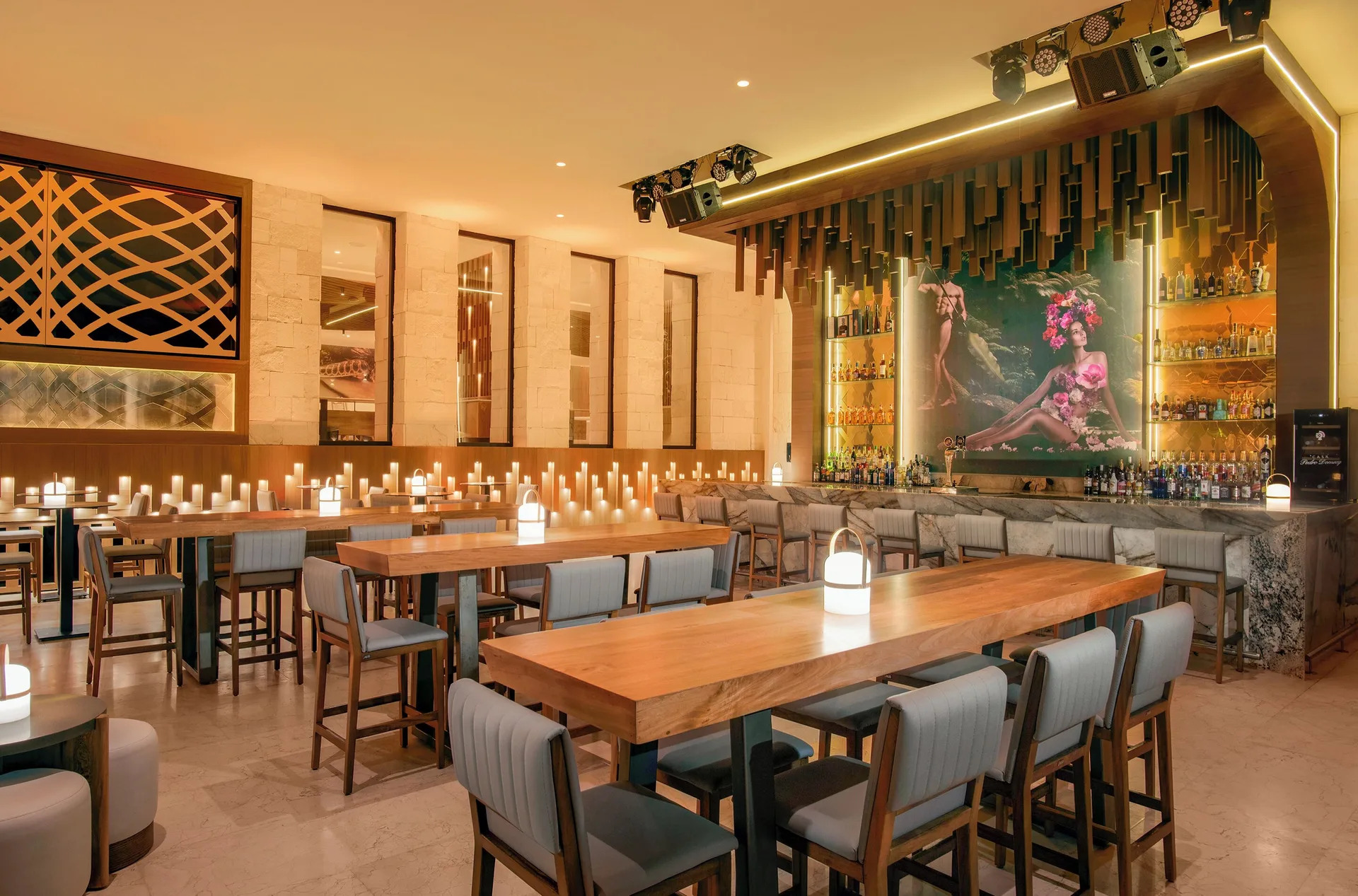 Candlelit lobby bar with high tables and backlit shelves at Desire Riviera Maya Resort.