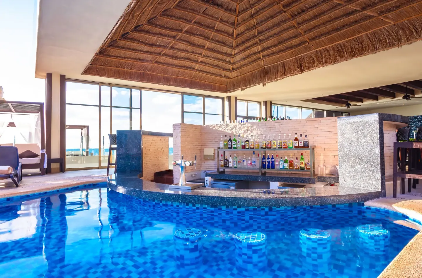 Indoor swim-up bar with blue pool seating at Desire Riviera Maya Resort.